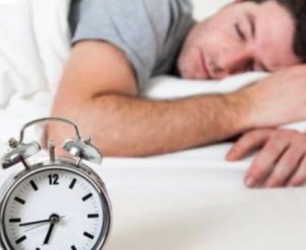 Clock with man sleeping on bed for 360's post about sleep affecting diabetes